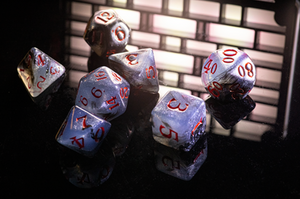 Set of polyhedral dice with red numbers on a reflective surface